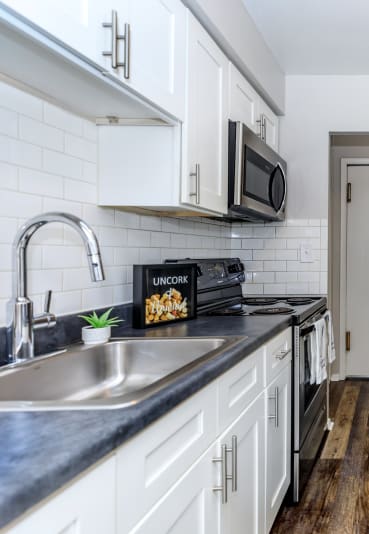 a kitchen with white cabinets and black appliances