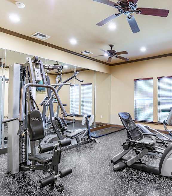 A spacious gym with a variety of equipment including treadmills, stationary bikes, and weight machines.