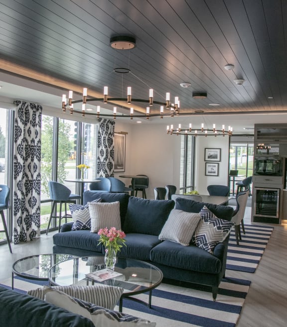 a living room and kitchen with a blue couch and chairs and a table at Enclave Crystal Lake Townhomes and Apartments, Illinois