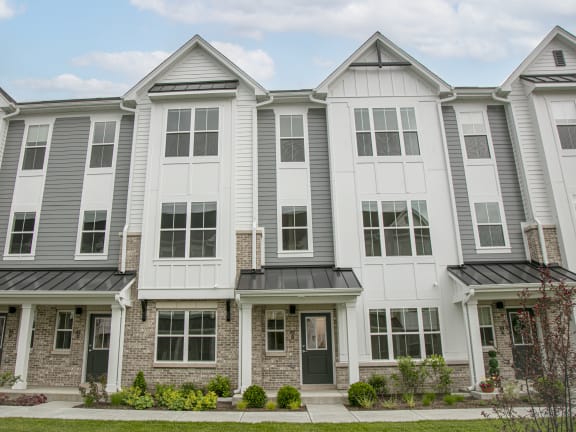 a group of townhomes with gray and white siding and a green lawn at Enclave Crystal Lake Townhomes and Apartments, Crystal Lake, Illinois