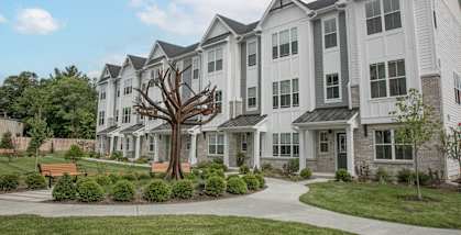 an exterior view of a large apartment building with a tree in the middle of a at Enclave Crystal Lake Townhomes and Apartments, Illinois, 60014