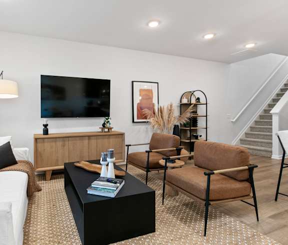 A living room with a white couch, a black coffee table, and a television.