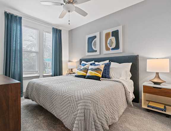A bedroom with a bed, nightstand, and a ceiling fan.