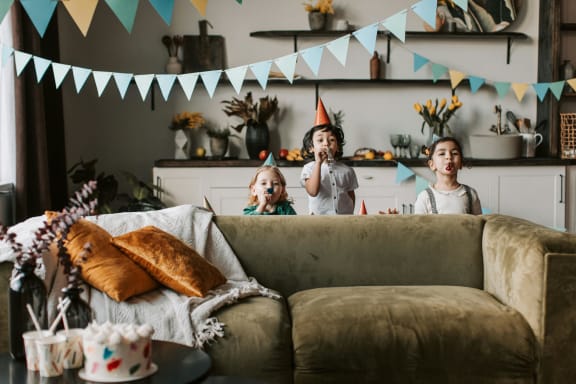 a group of children standing around a living room at a birthday party