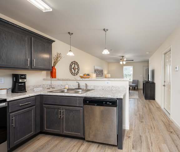 A kitchen with dark wood cabinets and a stainless steel dishwasher.