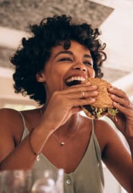 a woman eating a sandwich at a table in a restaurant