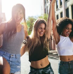 three young women dancing in the street