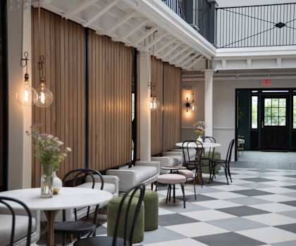 A restaurant with tables and chairs and a checkered floor.