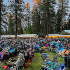 a large crowd of people sitting in lawn chairs in front of a stage
