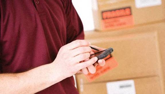A man in a black shirt is reaching for a box in a storage room.