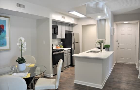 Modern apartment kitchen with stainless steel appliances, a breakfast bar, and adjacent dining area.