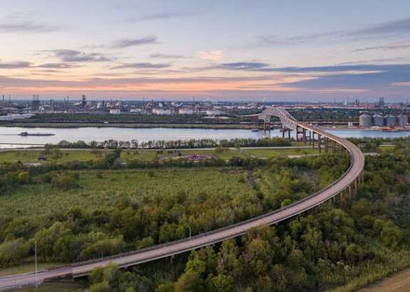 A bridge over a river with a city skyline in the background.