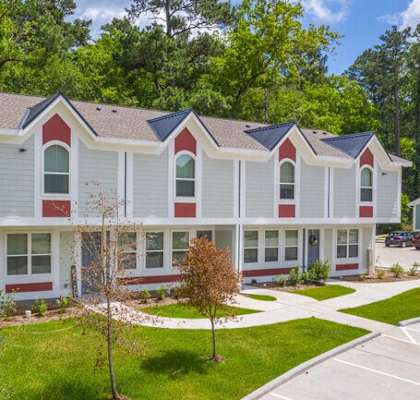 a white house with red and white siding and trees