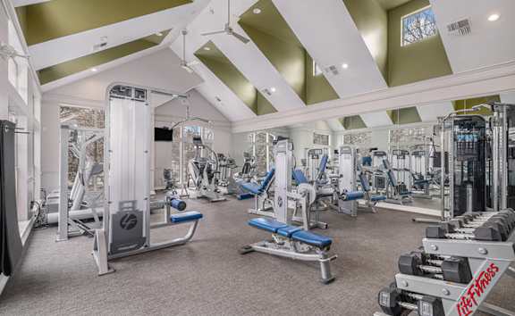 A spacious gym with a variety of equipment and a high ceiling.