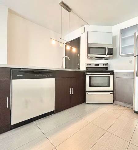 A kitchen with a refrigerator, oven, microwave, and sink.
