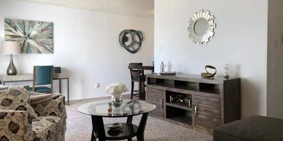 A living room with a sofa, a chair, a coffee table, and a painting on the wall.