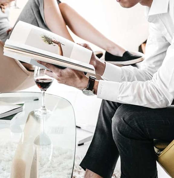 a man is holding a book and a glass of wine
