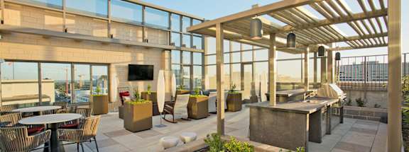 a patio with tables and chairs and a building with glass walls