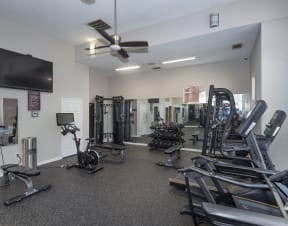 a spacious fitness center with cardio equipment and a flat screen tv