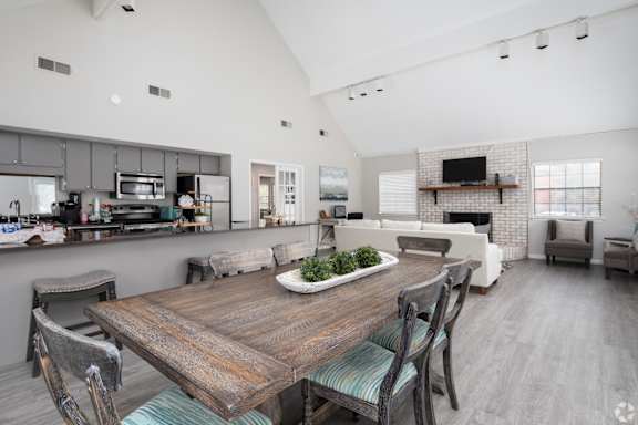 a dining area with a wooden table and chairs and a kitchen in the background