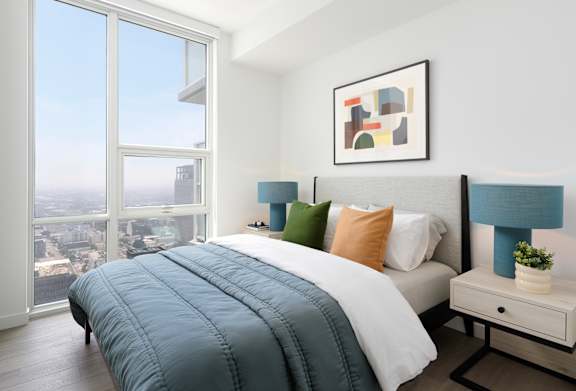 A bedroom with a large bed and a view of the city. at Olympic + Hill Apartments, Apartments, Los Angeles, CA