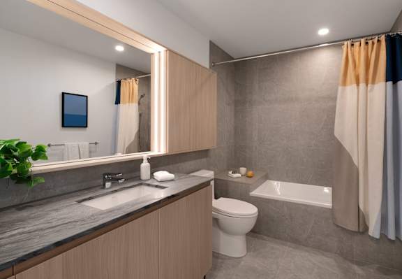 A modern bathroom with a toilet, sink, and bathtub. at Olympic + Hill Apartments, Apartments, Los Angeles, CA