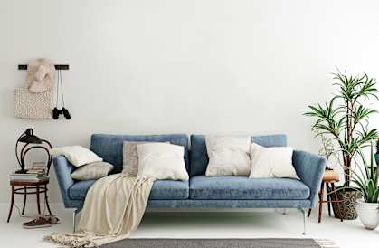 A blue couch with a white throw blanket on it.