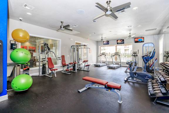 A gym with a variety of equipment including weights, a bench, and a fan.