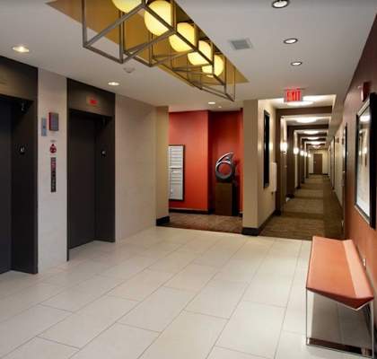 A long hallway with a bench and elevators.