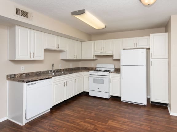 an empty kitchen with white cabinets and a stove and refrigerator