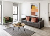 Thumbnail 3 of 12 - a living room with a gray couch and a coffee table and a green chair