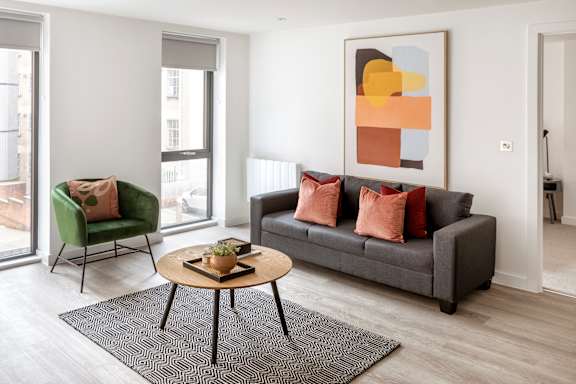 a living room with a gray couch and a coffee table and a green chair