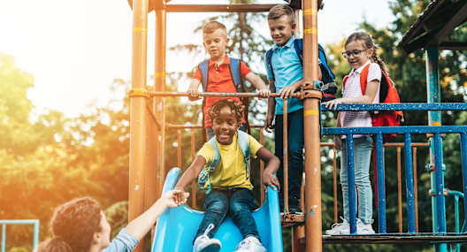 A child slides down a blue slide at a playground.