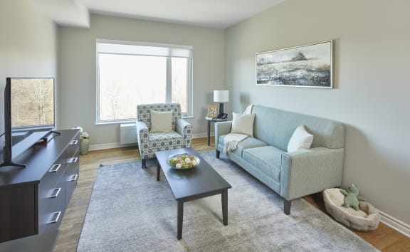 A living room with a blue couch and a coffee table with a bowl of fruit on it