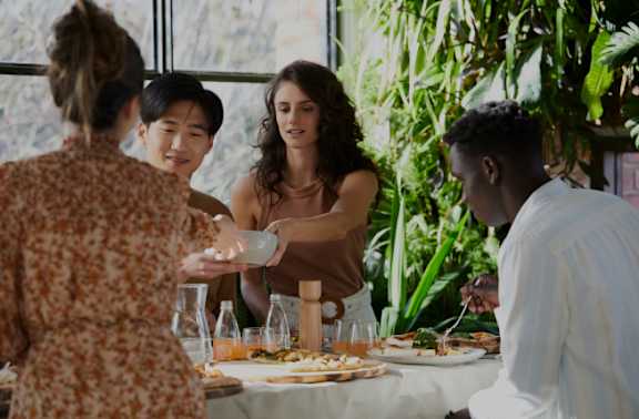 A group of people are gathered around a table with food and drinks.