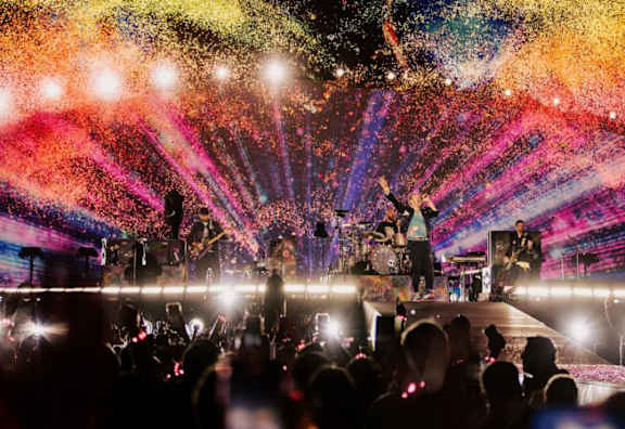 A band performing on stage with colorful lights and confetti.