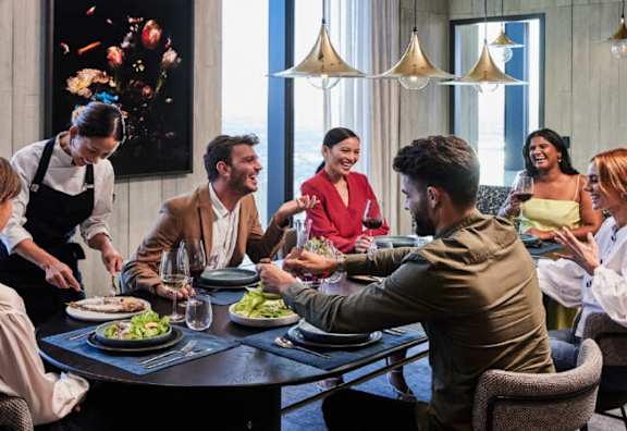 A group of people are gathered around a table, enjoying a meal and drinks.