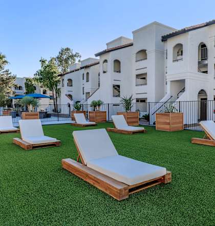 a group of white lounge chairs on a lawn in front of a building