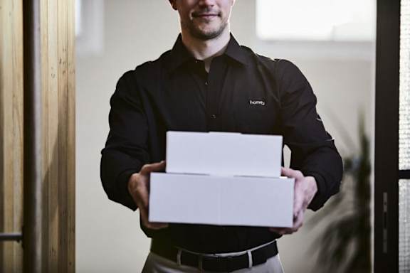 A man in a black shirt is holding a white box.