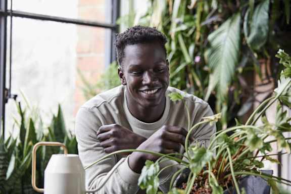 A man is smiling and looking at a plant.