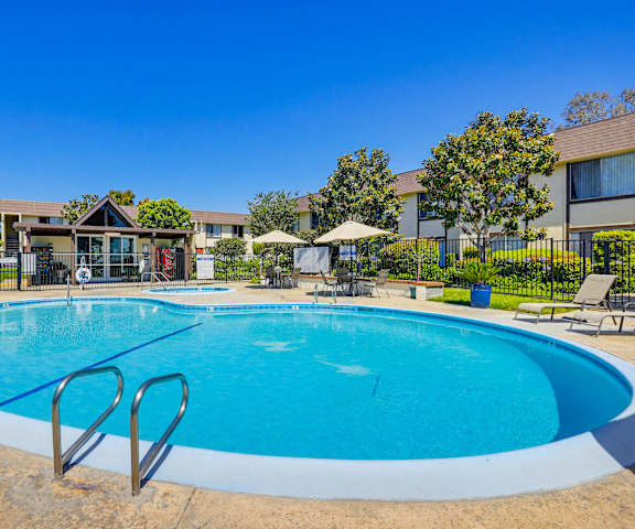 A large outdoor swimming pool with a diving board and lounge chairs.