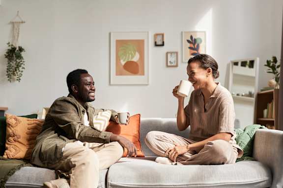 A woman with a joyful expression is leaning on a couch.