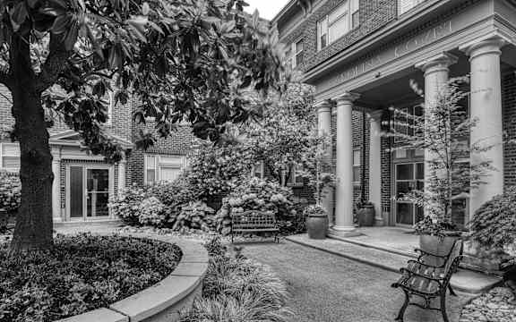 a black and white photo of a courtyard with a bench
