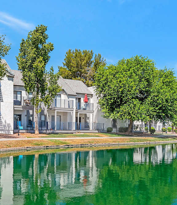 A swimming pool in front of a building with a blue sky in the background.
