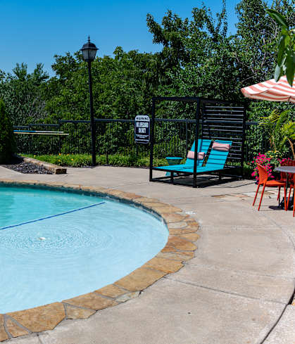 A large swimming pool surrounded by a concrete patio and a black fence.