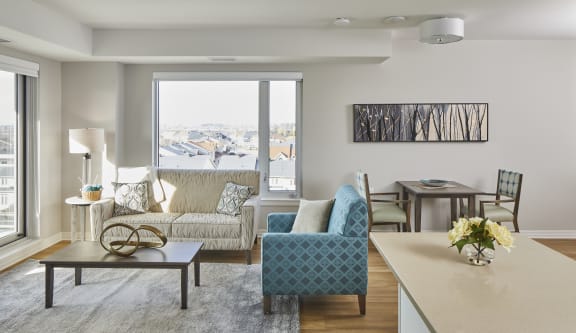 A living room with a couch, chairs and a table with a vase of flowers on it