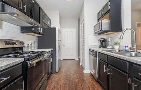 A kitchen with black cabinets and a white door in the background.