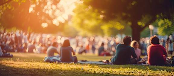 A group of people are sitting on the grass in a park.