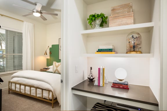 a bedroom with a bed and a desk with a lamp and books