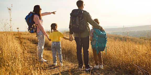 A family of four is hiking together in a field.
